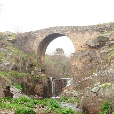 Puente de piedra con arco sobre arroyo natural