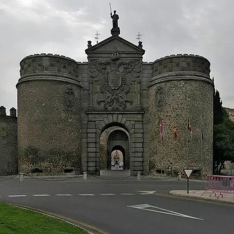Puerta fortificada de piedra bajo cielo nublado junto a vía urbana.