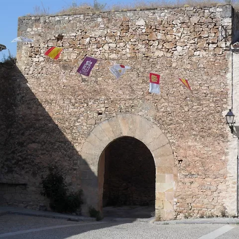 Puerta de piedra con arco en plaza empedrada
