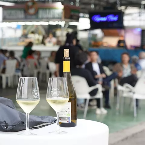 Botella de vino y dos copas sobre una mesa alta en un evento