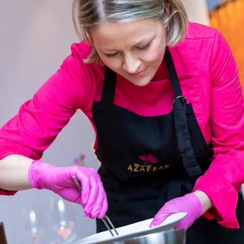 Chef emplatando con uniforme rosa y guantes