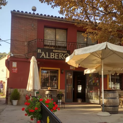 Fachada de restaurante con terraza, sombrillas y macetas con flores.