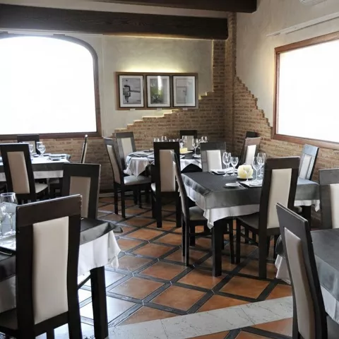 Comedor acogedor con manteles grises, sillas altas y paredes de ladrillo.