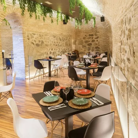 Comedor de estilo rústico con paredes de piedra y mesas cuadradas.