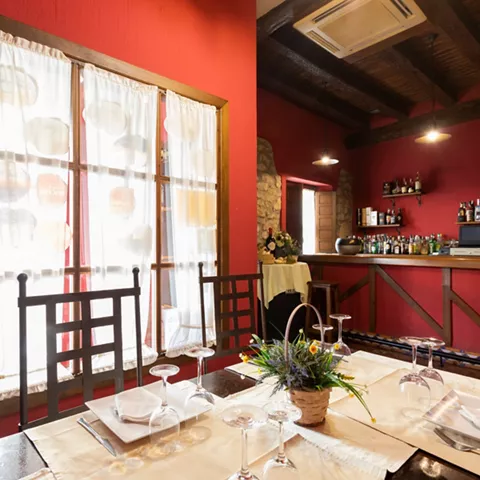 Salón con barra y mesas junto a ventanales