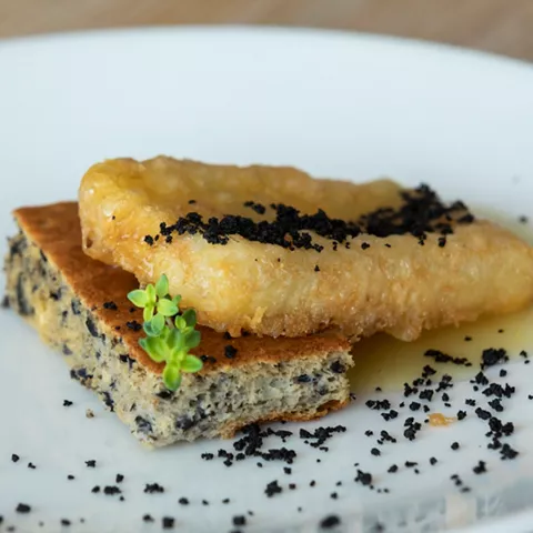 Bacalao confitado sobre pan y migas negras