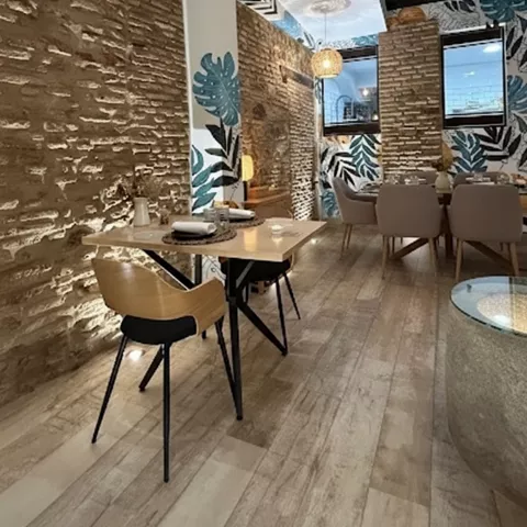 Salón estrecho con mesas montadas, columnas decoradas y paredes de ladrillo.