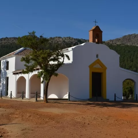Ermita blanca en un claro con montañas al fondo