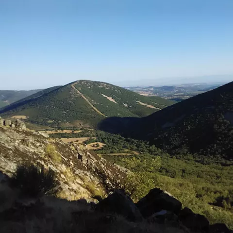 Vista de valle y laderas montañosas desde un mirador rocoso.
