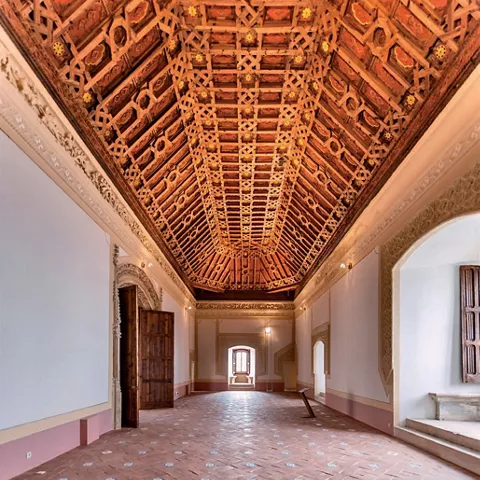 Salón histórico con artesonado de madera tallada.