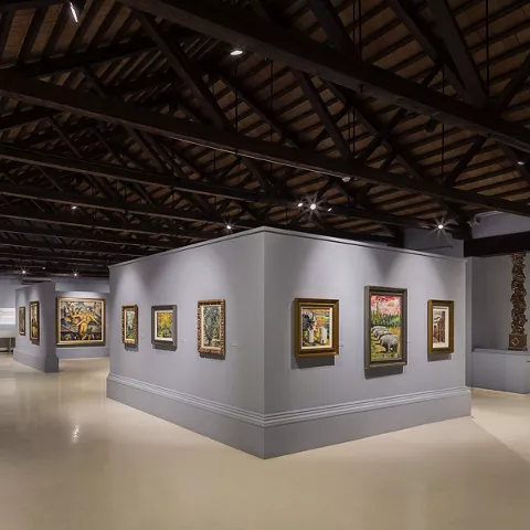 Sala amplia con techumbre de madera y obras en paneles centrales