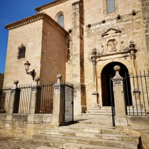 Fachada de templo de piedra con escalinata y reja.