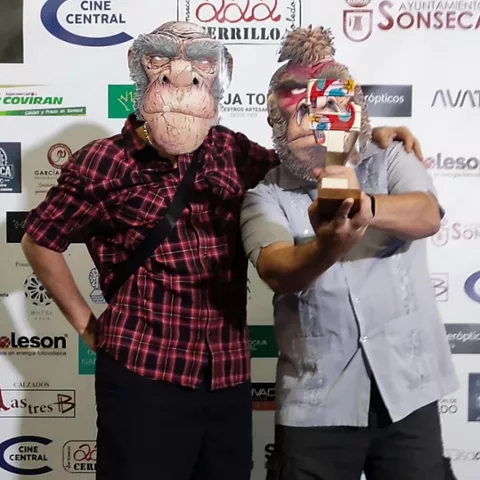 Dos personas con máscaras de mono posan con un premio