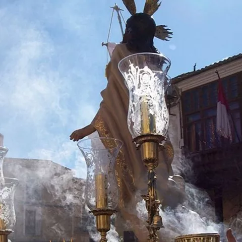 Paso religioso con figura elevada entre humo de incienso y faroles