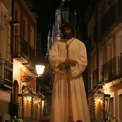 Imagen de Cristo atado y con túnica blanca, iluminado por faroles, en una calle nocturna.