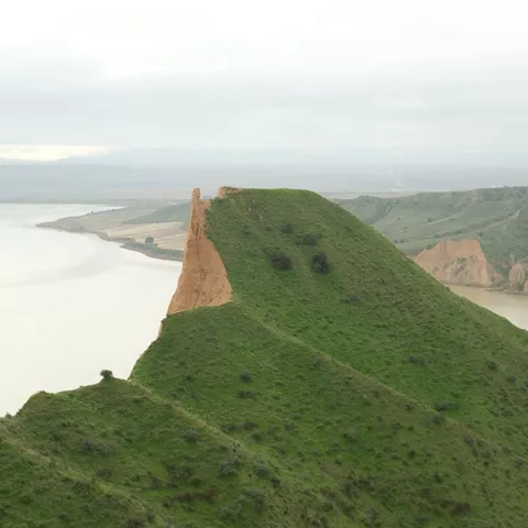 Cañón erosionado con laderas rojizas y un cauce seco en el fondo.