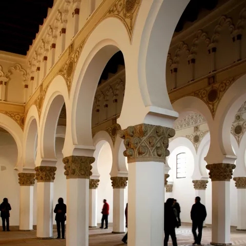 Personas recorriendo espacio monumental con techumbre de madera.