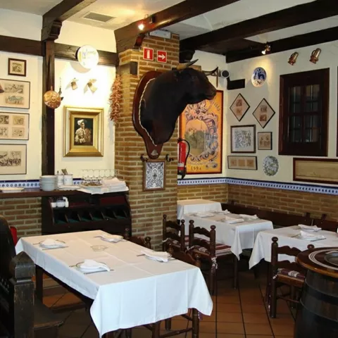 Comedor clásico con mesas montadas, paredes decoradas y vigas vistas.