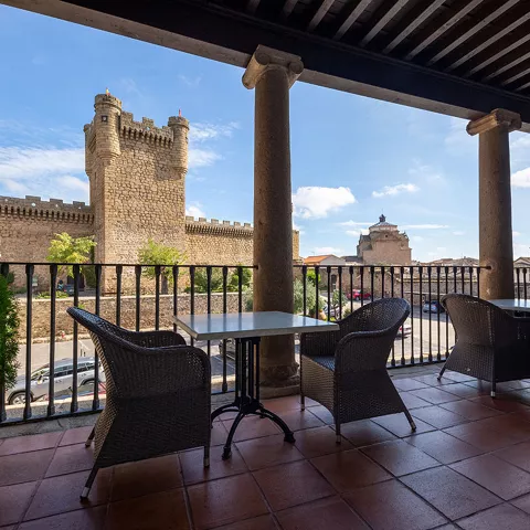 Terraza porticada con vistas a una fortificación.