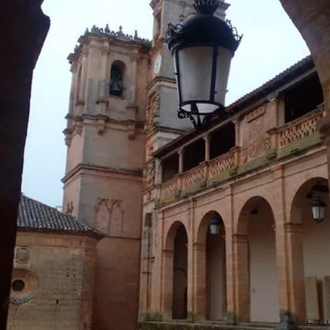 Detalle arquitectónico de torres de piedra vistas desde un patio con farol antiguo.
