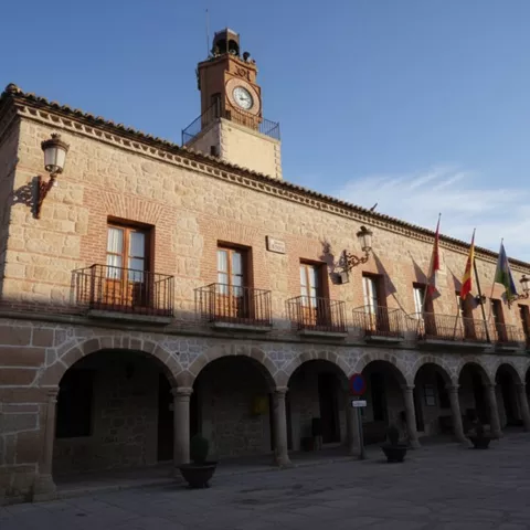 Perspectiva en ángulo del mismo edificio de piedra con arquería, destacando la textura de los sillares y los balcones de hierro.