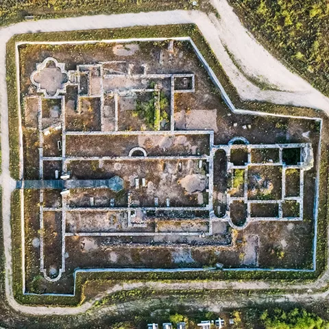 Vista aérea cenital de un yacimiento con trazado rectangular y caminos alrededor.