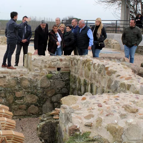 Grupo de personas visitando ruinas con muros de piedra y estructuras excavadas.