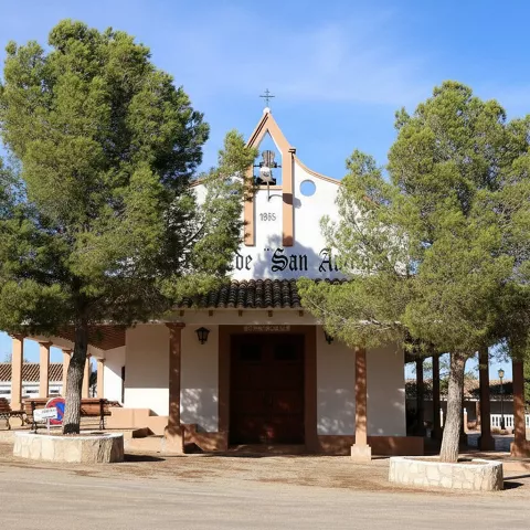 Ermita blanca rodeada de pinos y espacio abierto