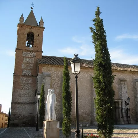 Iglesia histórica con torre campanario y entorno ajardinado