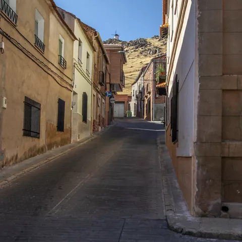Calle empedrada con casas y un cerro al fondo.