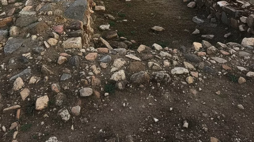 Ruinas de antiguas construcciones de piedra en paisaje abierto al atardecer.