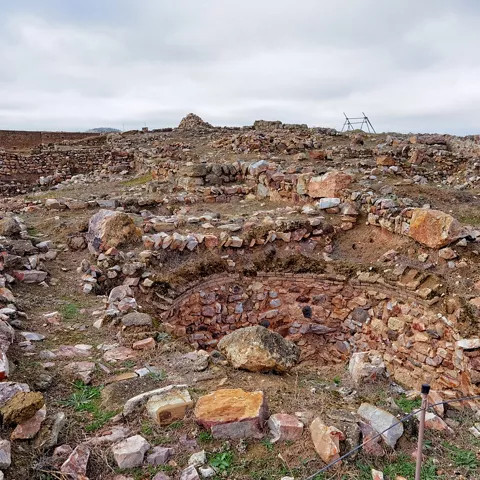 Ruinas de muros de piedra en un yacimiento al aire libre.