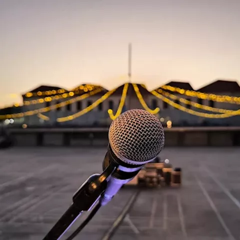 Micrófono en primer plano frente a un escenario al atardecer.