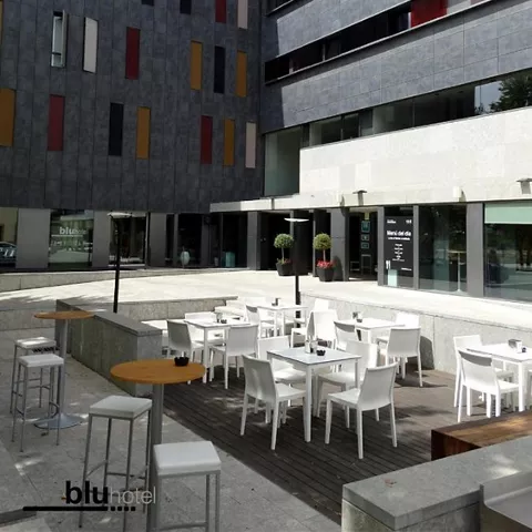 Terraza exterior con mesas blancas en patio urbano moderno.