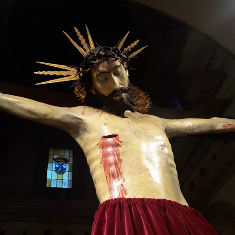 Escultura religiosa de cuerpo entero con paño rojo en el altar