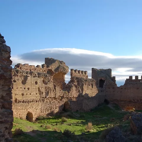 Vista interior de murallas de piedra con torres y restos de antiguas estancias.