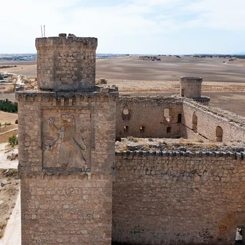 Torre cuadrada y muralla con vistas a campos abiertos.
