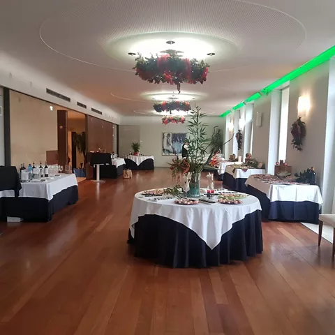 Sala de eventos con mesas vestidas, decoración floral y suelo de madera.