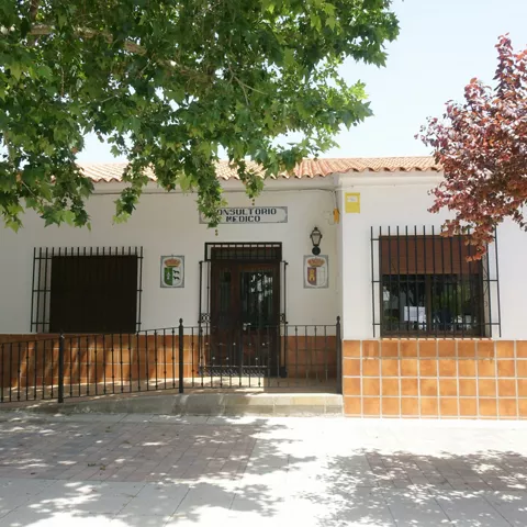 Fachada de centro médico bajo la sombra de dos árboles