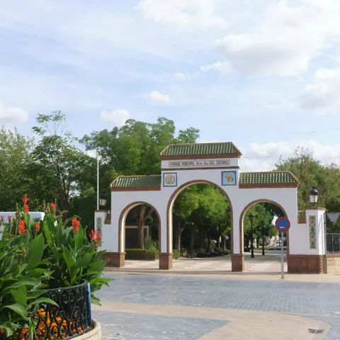 Estatua femenina junto a la entrada de un parque con arcos