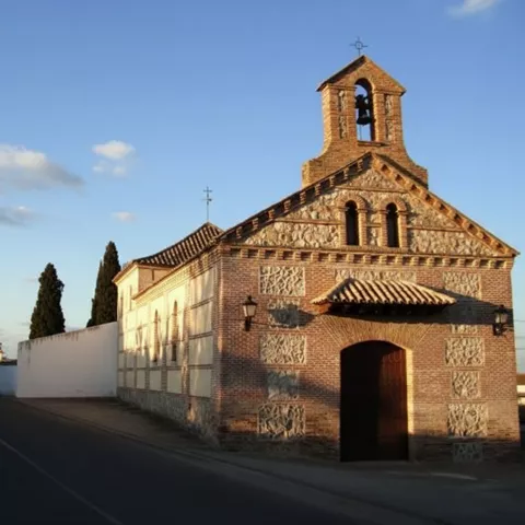 Iglesia de ladrillo y piedra junto a una calle al atardecer