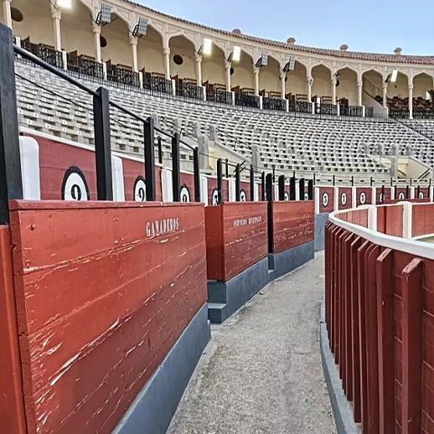 Pasillo curvo junto a la arena con barreras de madera y gradas.