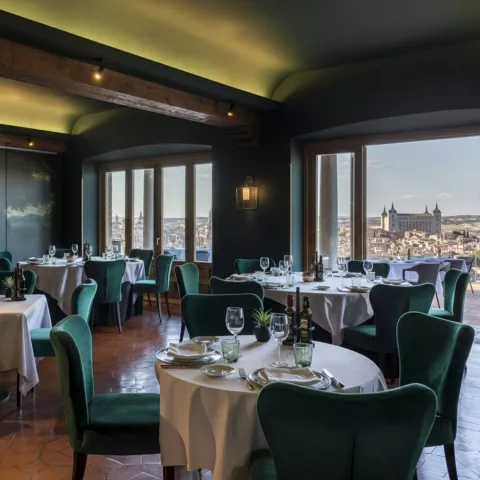 Comedor con sillas verdes y grandes ventanales con vistas