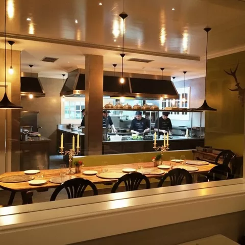 Mesa larga preparada frente a una cocina acristalada