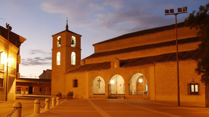 Iglesia iluminada de noche en plaza vacía