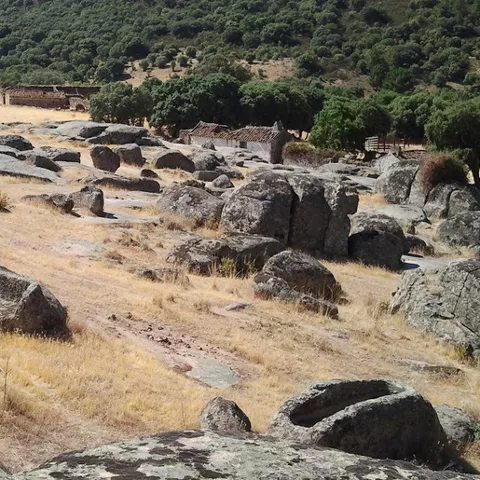 Paisaje de rocas y antiguas sepulturas excavadas en ladera natural.