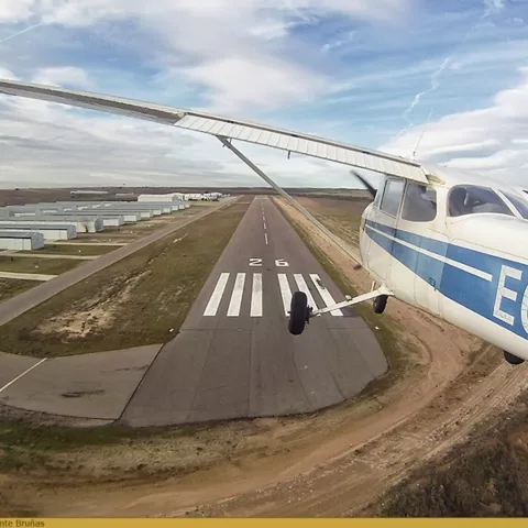 Avioneta en aproximación final a pista asfaltada vista desde el aire.