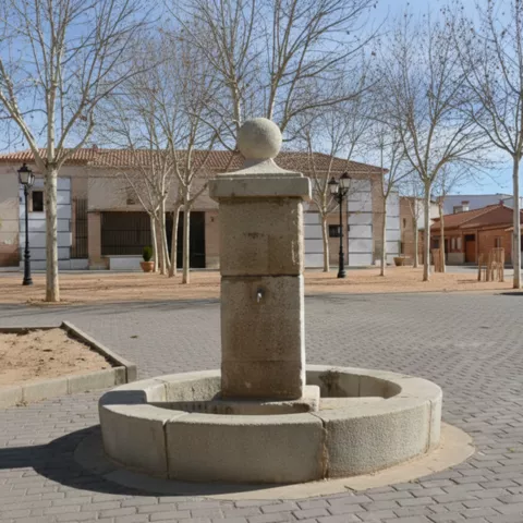 Fuente de piedra en una plaza tranquila con arbolado