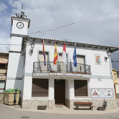 Edificio municipal blanco con torre del reloj y banderas