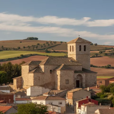 Iglesia de piedra entre viviendas y colinas suaves